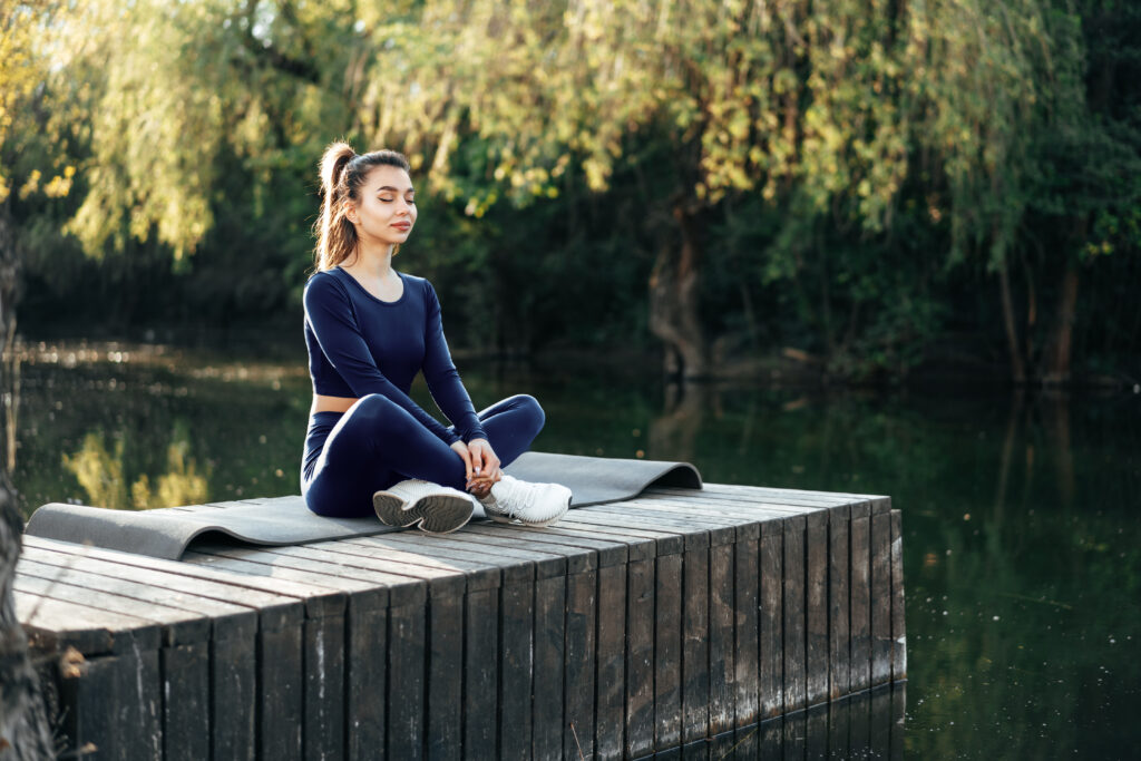 young woman on a yoga mat relaxing outdoors